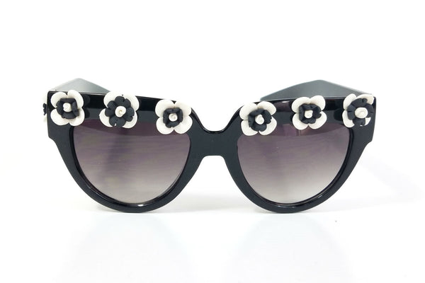 shiny black plastic frame sunglasses with applied hand-molded black & white flower trim at brow and arms and gradient smoke lens