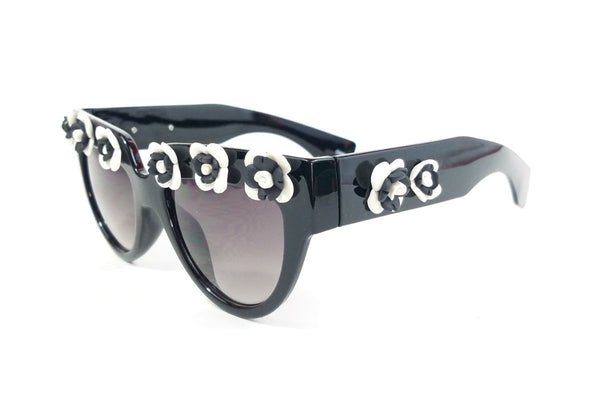 shiny black plastic frame sunglasses with applied hand-molded black & white flower trim at brow and arms and gradient smoke lens