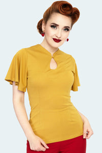 A model wearing a mustard colored knit top with flutter style short sleeves and a keyhole detail neckline. The top is hip length and is untucked