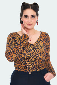 A model wearing a long sleeved v-neck top in a faux wrap style. It is in a warm orange and brown leopard print with black spots 
