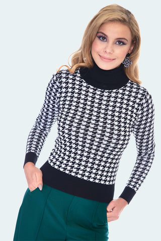 A model wearing a turtleneck sweater with a white and black houndstooth pattern and solid black neck, cuffs, and bottom hem 