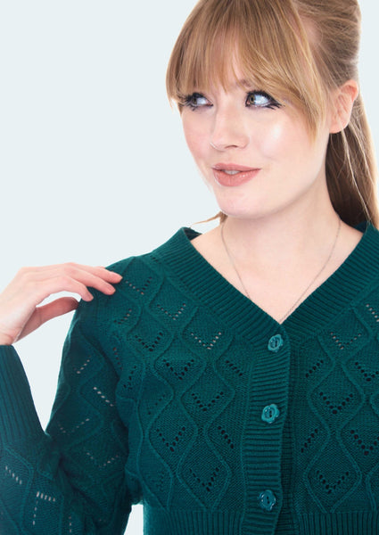 A close up shot of the model wearing the cardigan to show the detail of the openwork and flower buttons