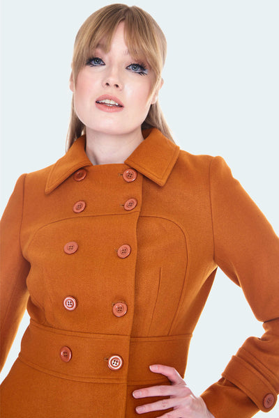 Burnt orange wool double breasted coat with fit and flare silhouette and pockets. Hits at knee. Shown on model up close and fully buttoned up 