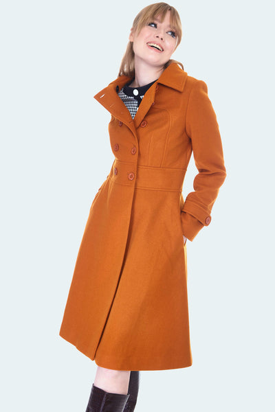 Burnt orange wool double breasted coat with fit and flare silhouette and pockets. Hits at knee. Shown on model At 3/4 pose and half buttoned down